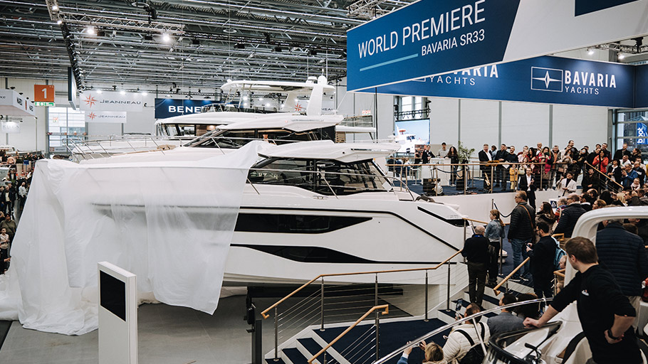 Exhibition stand with several yachts on display and many visitors at a boat show.