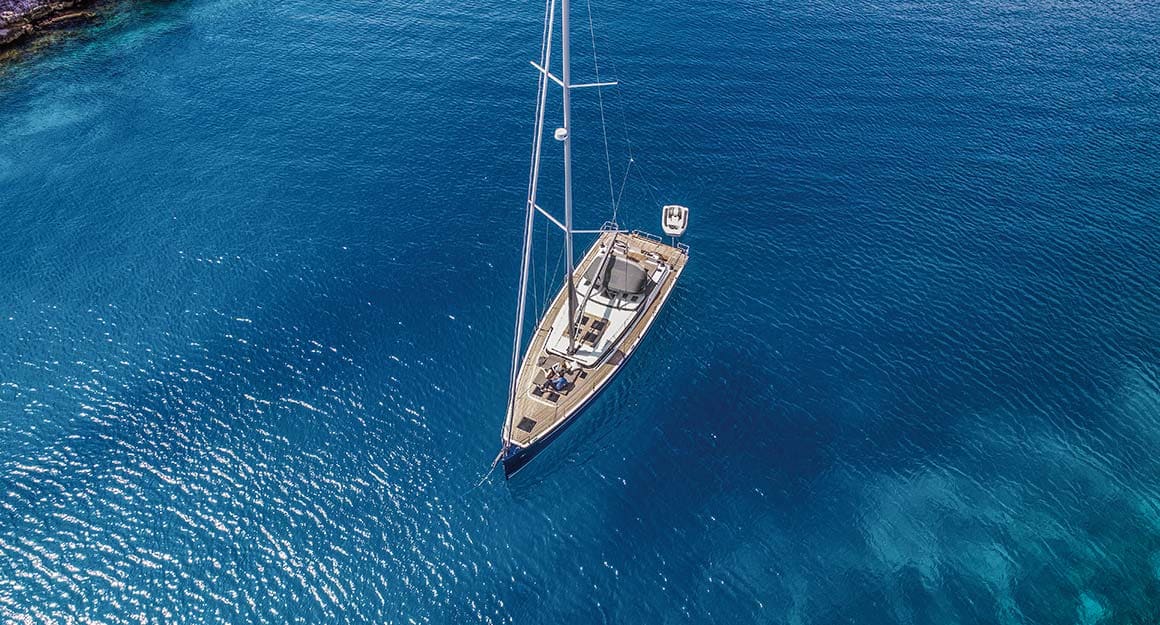 Anchored boat from above on clear calm blue water.