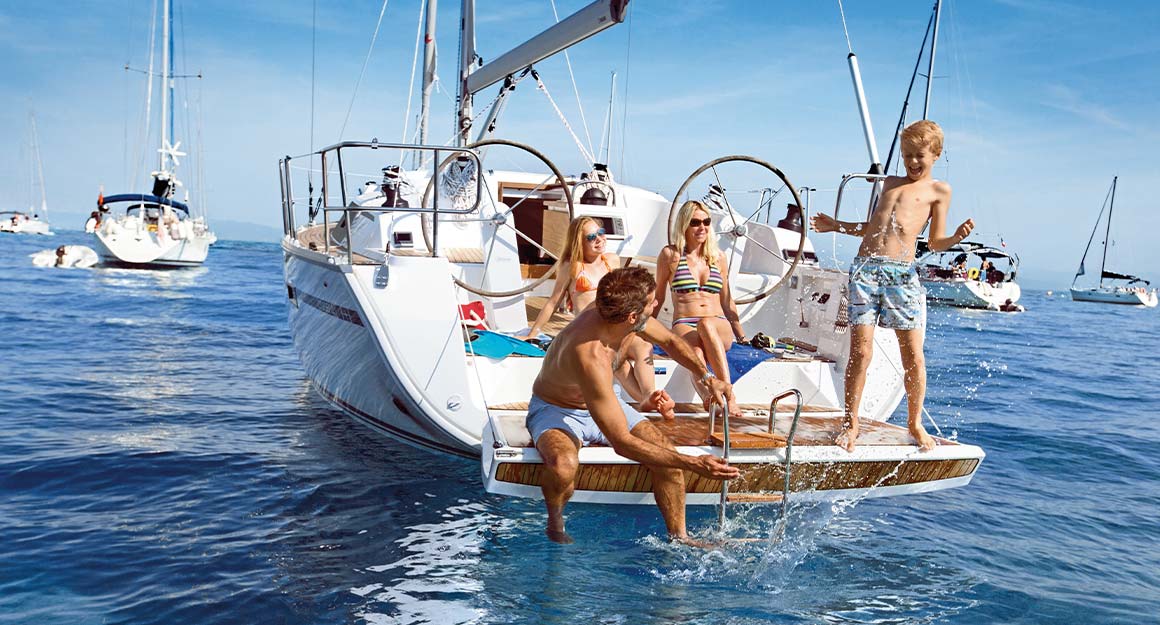 Rear view of an anchored boat with a cheerful family on the bathing platform.