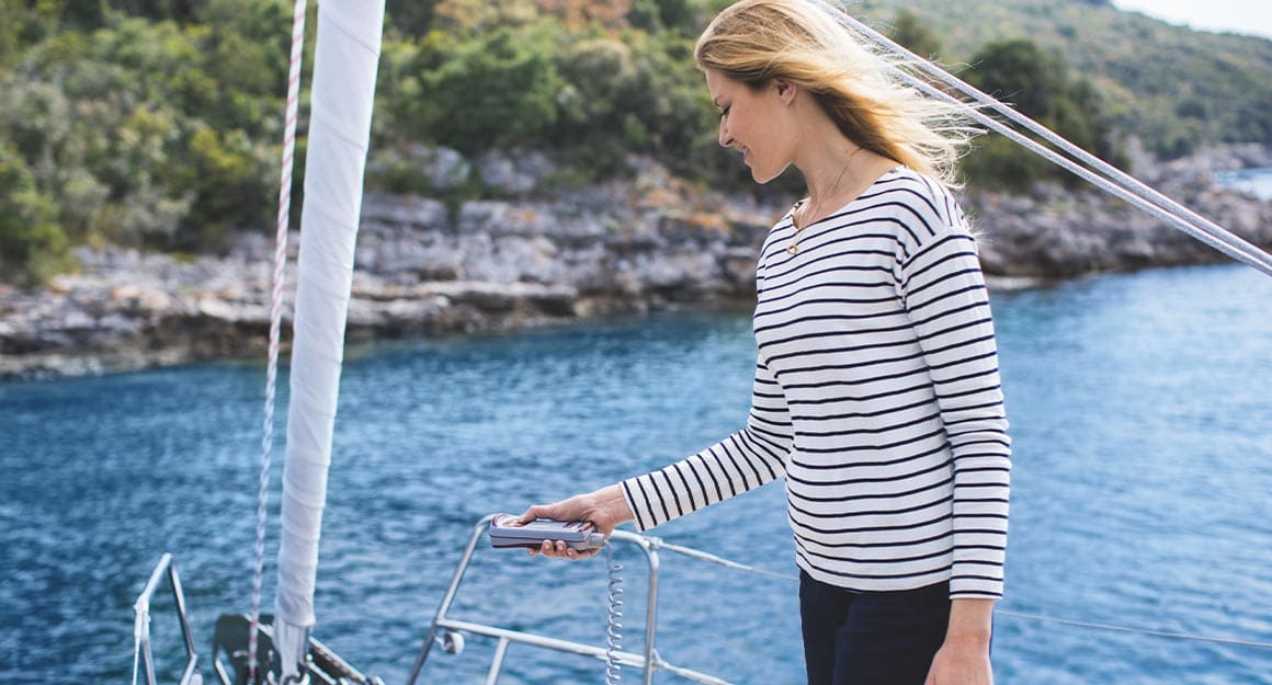 Woman in striped jumper on board a boat operating the remote control for the anchor winch.