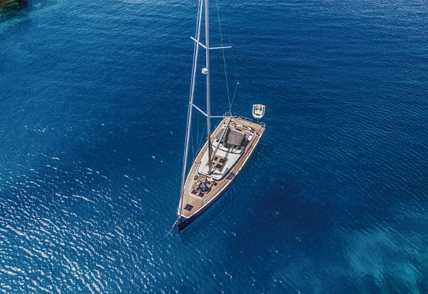 Anchored boat from above on clear calm blue water.