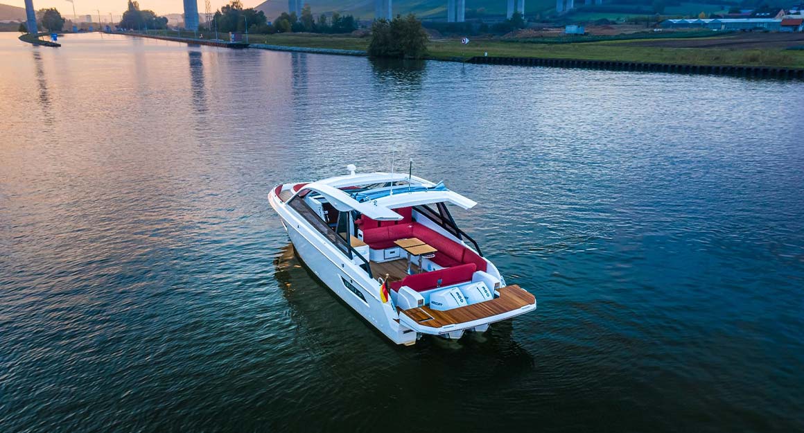 The BAVARIA VIDA 33 on a large calm river with the shore and sunset in the background.