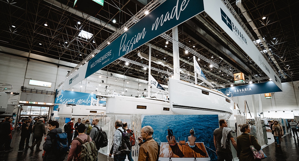 View of the boot exhibition hall with numerous yachts, lights and visitors.
