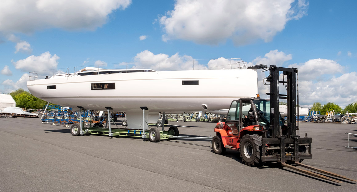 Transporting a motorboat using a forklift truck on a rolling surface with a cloudy sky.