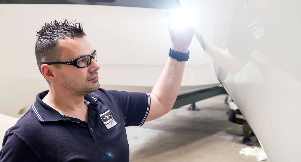 Man with dark blue shirt and glasses, working on the shiny surface of the torso.