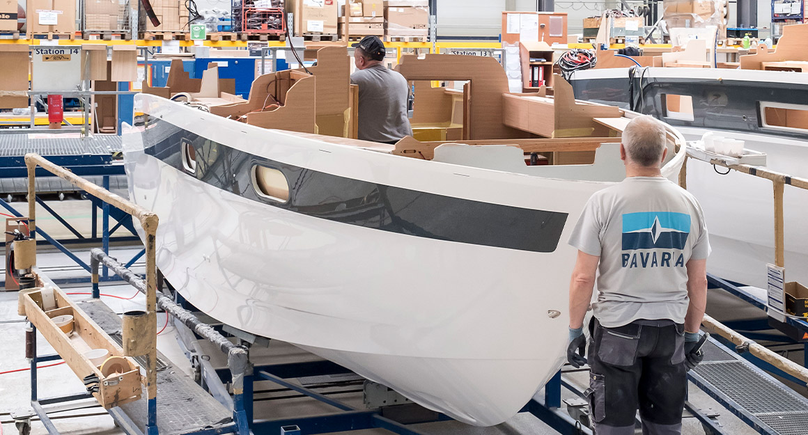 View of white-blue hull with built-in cabin, one worker at the front and one at the rear.