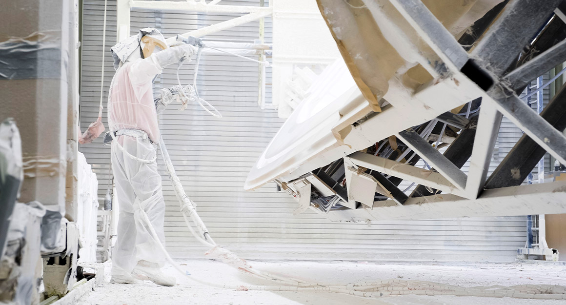 Man in white full-body protective clothing during the laminating process.