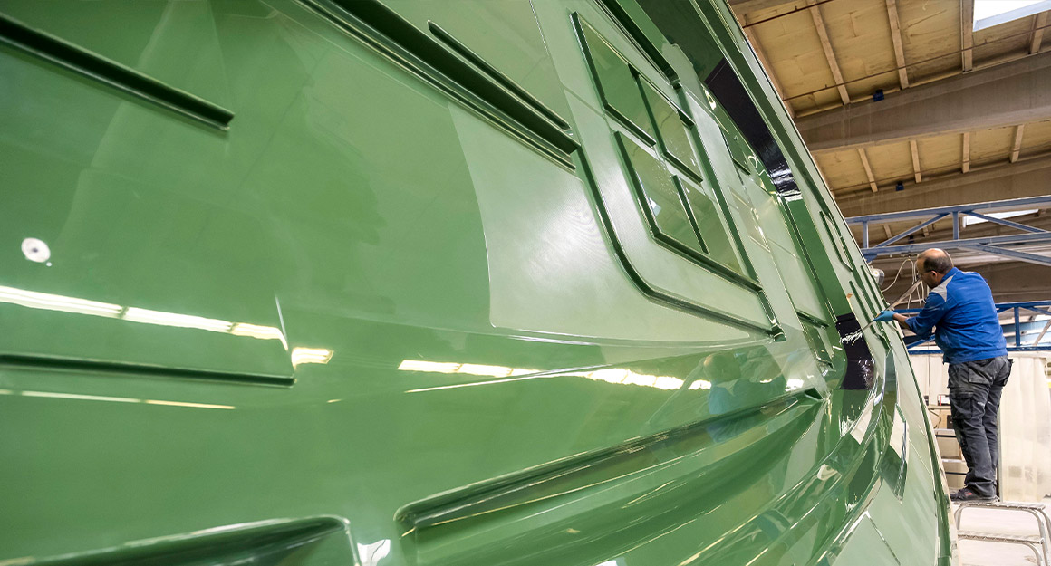 Green laminated boat mould with a man working on it in the background.