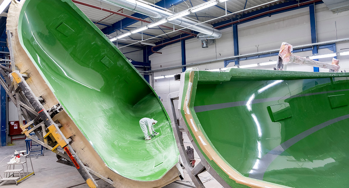 Two halves of a large green boat shell mould.