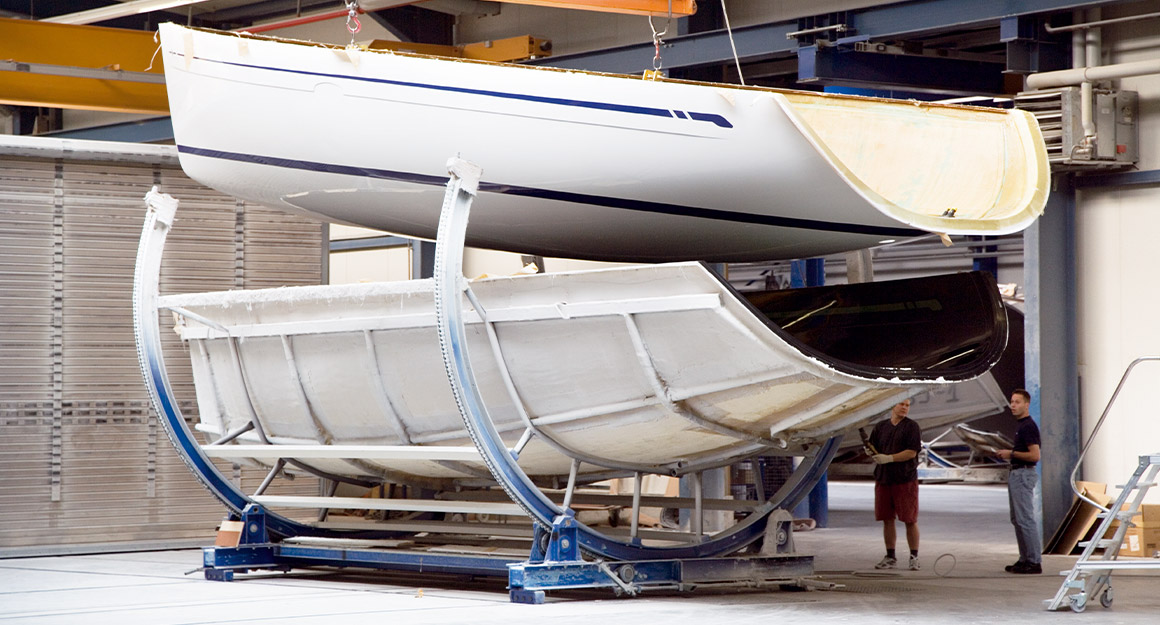 two white boat shells stacked on top of each other with two men next to them.
