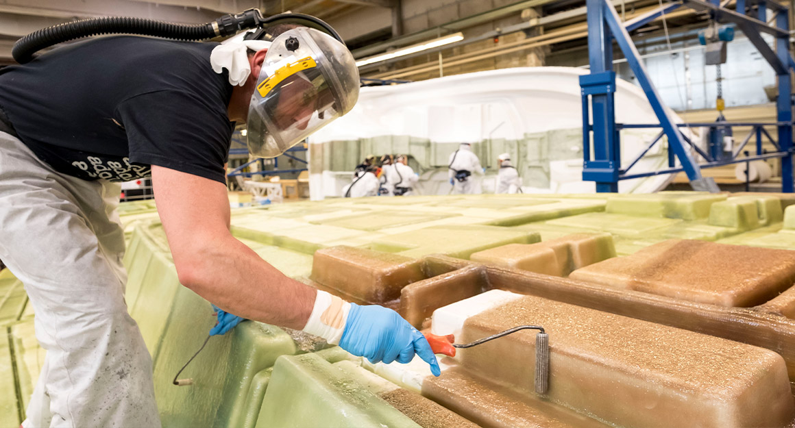 Man with protective mask and gloves laminates smaller boat moulds.