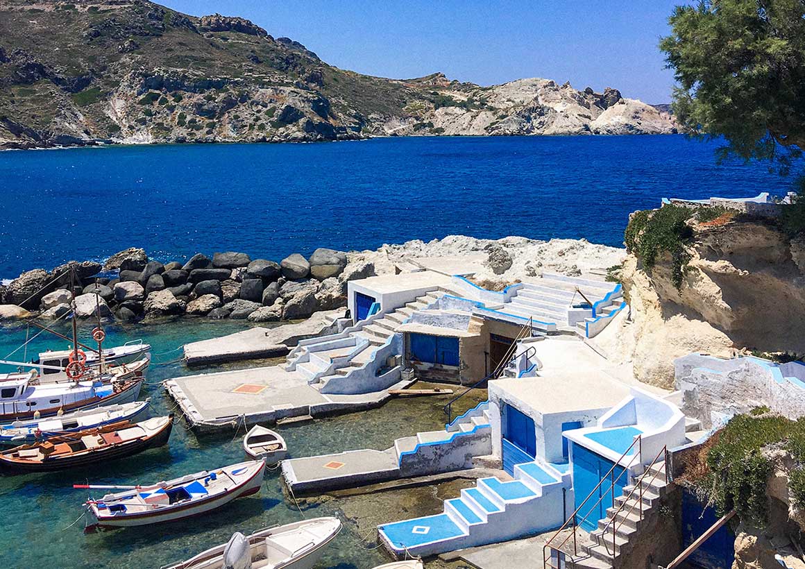 Tiny jetty with bungalows by the sea with a coastline in the background.
