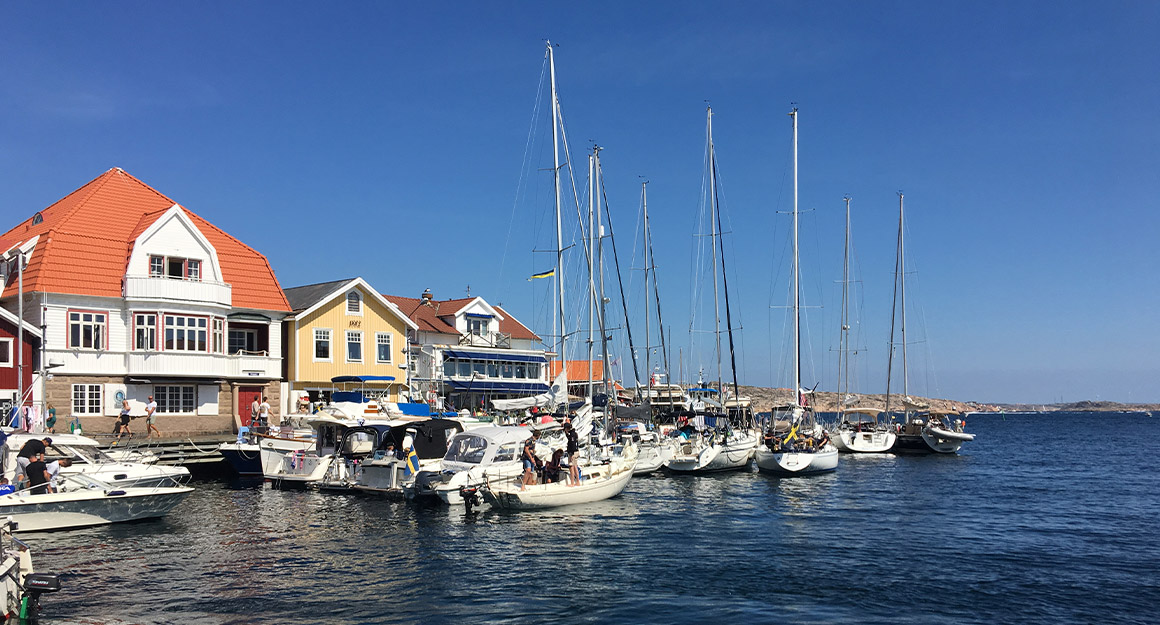 Small harbour with a few moored boats, dark blue water and colourful houses.