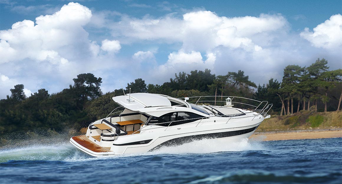 Side view of a motorboat on the water with wooded coastline in the background.