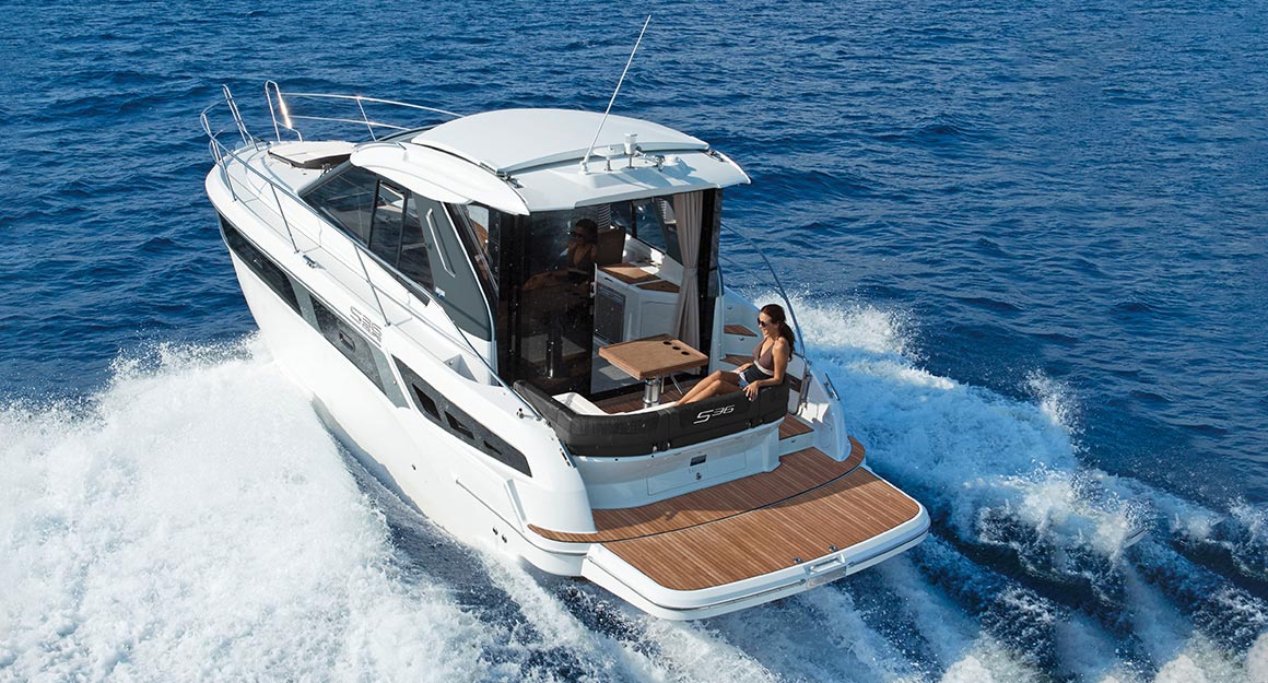 Hull of a motorboat on the water with a woman sitting relaxed.